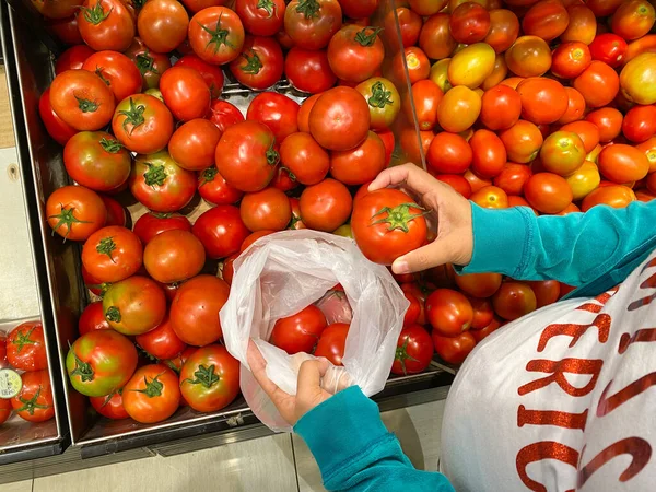 Беременная женщина покупает помидоры в магазине. — стоковое фото