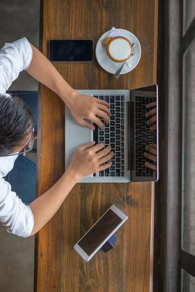 Manos humanas escribiendo portátil con teléfono inteligente y tableta en la mesa — Foto de Stock