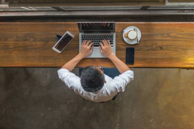 Kafeteryada laptopuyla çalışan Asyalı işadamı.