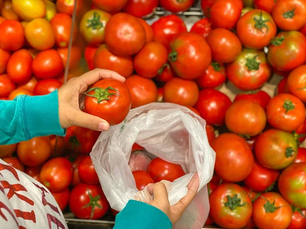 Фото женщины, покупающей красный помидор в продуктовых магазинах — стоковое фото