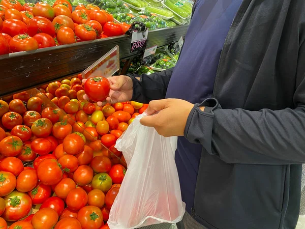 Человек, покупающий помидоры в продуктовом магазине или супермаркете — стоковое фото