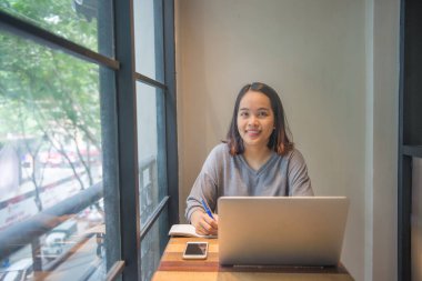 Gülümseyen Asyalı genç öğrenci notlar yazıyor.