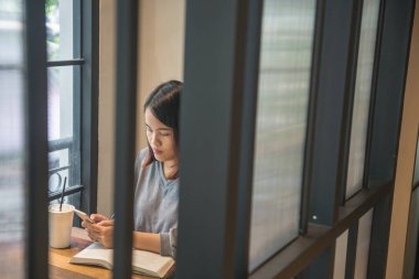 Kitap okurken arkadaşlarıyla mesajlaşan Asyalı kadın