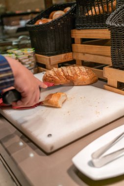 Kadın açık büfede ekmek kesiyor.