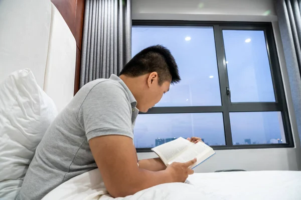 Oldalnézet férfi olvasás könyv az ágyban — Stock Fotó
