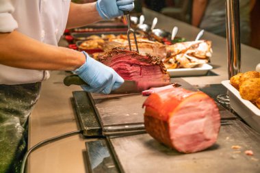 Şef çatal ve bıçakla biftek kesiyor.