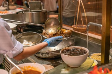 Şef mutfakta deniz ürünleri pişiriyor.