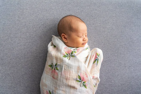 New born Asian infant sleeping on grey background