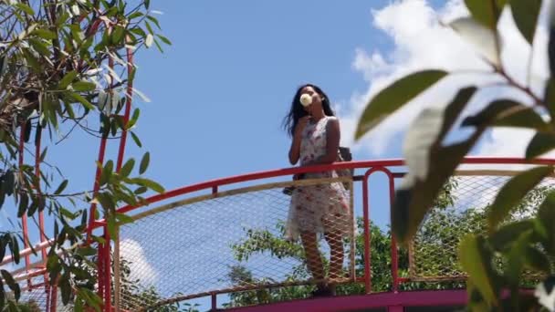 Obekymmerslös ung kvinna på balkongen luktar en vit dahlia blomma. — Stockvideo