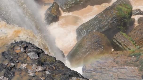 Una vista sul fondo della cascata con rocce gigantesche e acqua che scorre arancione. — Video Stock