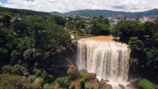 Flygflygning över ett regnskogs vattenfall med enorma klippor, by och berg — Stockvideo