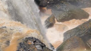 Şelalenin güçlü akışı ve büyük kayaların üzerinde akan su sıçraması..