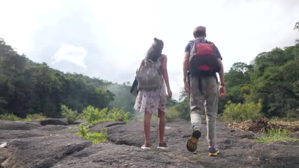 Cinemático de homem e mulher jovens com mochilas andando juntos no parque natural. — Vídeo de Stock