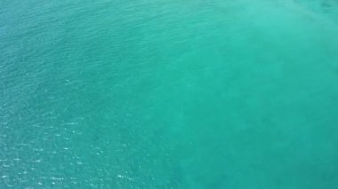 İnsansız hava aracı, yaz günü sakin bir turkuaz mavi okyanusun üzerinde uçar..