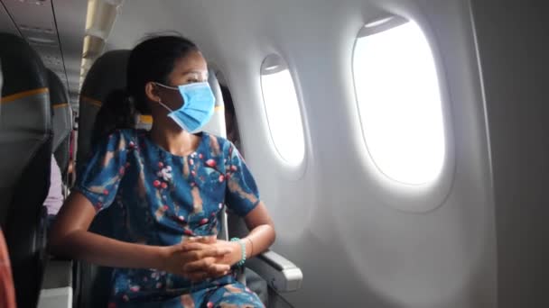 비행기 안에 파란색 마스크를 쓴 아시아 여성이 창밖을 내다보고 있습니다. — 비디오