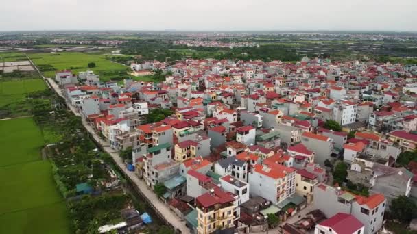 Areal utsikt över en förort stad med moderna hus och gröna paddyfält. — Stockvideo