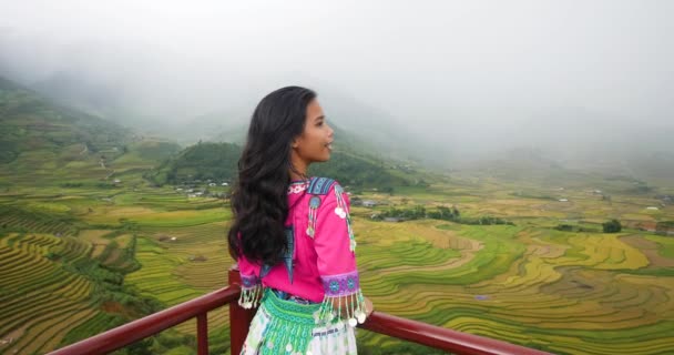 Азиатская девушка в культурной одежде с видом на мезоризующие рисовые террасы. — стоковое видео