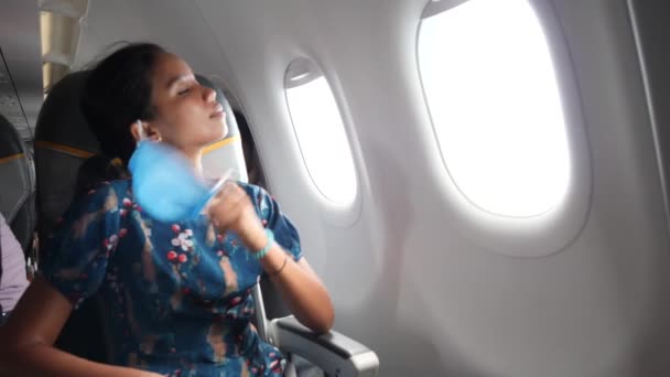 Femme asiatique à l'intérieur de l'avion enlever son masque et prend une profonde respiration. — Video