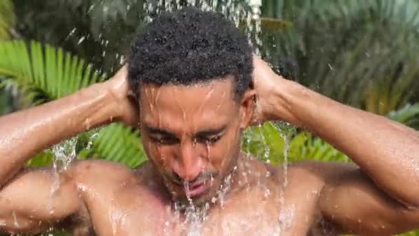 Портрет сексуального молодого черного мужчины, принимающего душ на открытом воздухе в летний день. — стоковое видео
