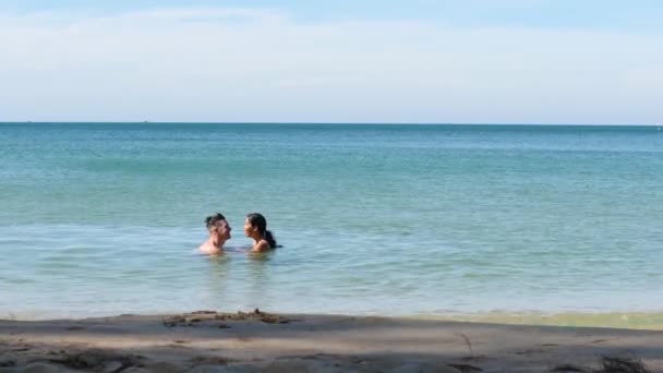 Zoet jong paar zwemmen in het strand praten, lachen en glimlachen in de oceaan. — Stockvideo
