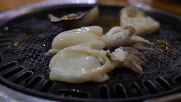 Vista de cerca de conchas frescas y sepias a la parrilla con aceite en una estufa de parrilla — Vídeos de Stock