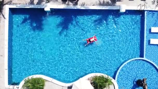 Vista aérea de arriba hacia abajo de un hombre en una cama inflable de aire en la piscina. — Vídeos de Stock