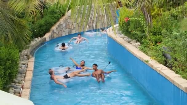 Personas en el parque acuático cabalgando en el flotador en el río artificial perezoso. — Vídeos de Stock