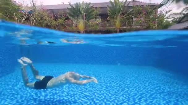 Spalato colpo subacqueo di un uomo che nuota in piscina in una giornata estiva in un resort. — Video Stock