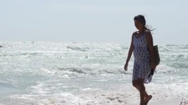 Sahilde yürüyen hamile bir Asyalı kadının yavaş çekim görüntüleri..