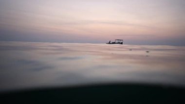 Bir balıkçı teknesi ve yüzen bir adamla denizdeki su ve gökyüzünü ikiye böleceğiz.