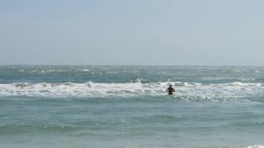 Bir yaz günü dalgalı denizde yürüyen tanınmayan bir adam..