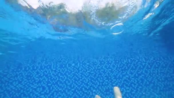 Podvodní scéna muže ležícího na dně bazénu, jak dělá bublinkové kroužky. — Stock video