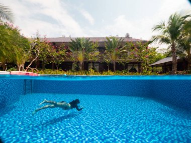 Tropikal bir villa ve mavi bir yüzme havuzunu su altında bir kadınla paylaşmak..