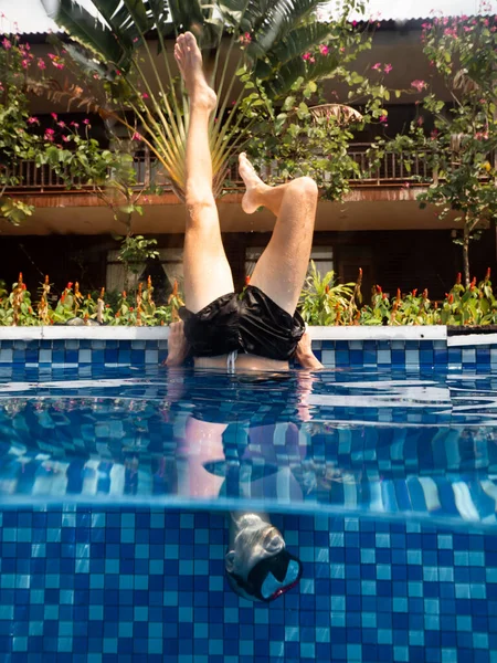 年轻男子戴着潜水面罩，倒立在游泳池边 免版税图库图片