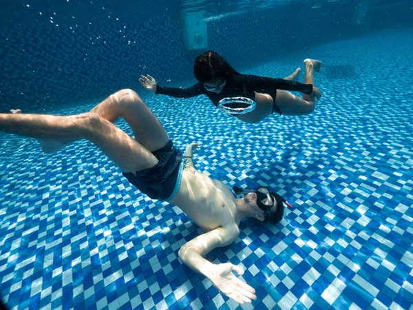 Undervattensutsikt i poolen av en ung kvinna och man på en sommardag. — Stockfoto