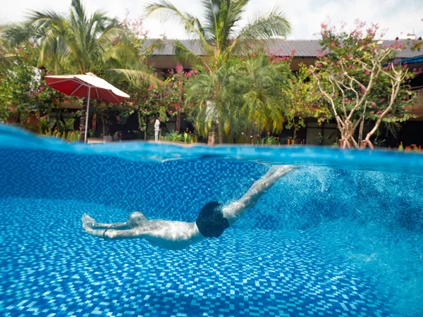 Split photo of a man underwater in the swimming pool in the holiday villa Royalty Free Stock Images