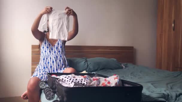 Genç ve mutlu bir kadın yatak odasında bebek kıyafetlerini katlıyor, hastane çantasını hazırlıyor.. — Stok video