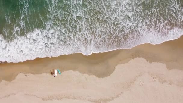 Aerial view of surf waves brushing and breaking on the white sandy seashore on a summer day. — Stok video