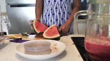 Mutfakta taze karpuz kesen hamile bir kadının yarı vücut görüntüsü..