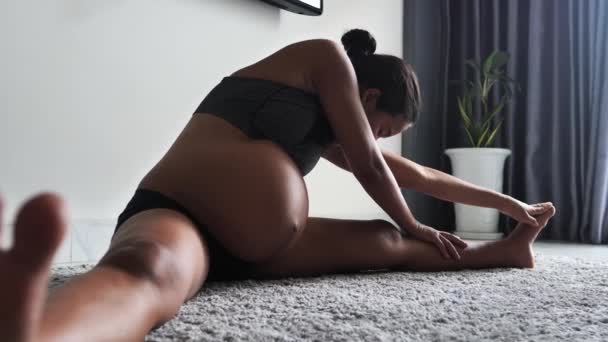 Mujer embarazada haciendo ejercicio en casa, estirando las piernas y respirando. — Vídeos de Stock