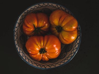 Seramik tabakta İspanyol domatesleri. Siyah arka plan. Havadan. Düz Yat.