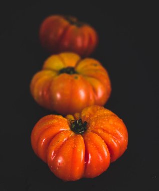 Arka arkaya İspanyol domatesleri. Siyah arka plan. Açı görüşü. Alan derinliği.