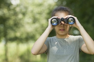 Pretty young girl exploring the environment with a binocular clipart