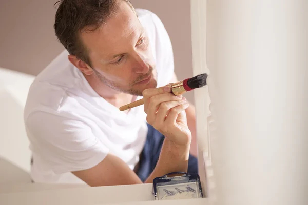 Joven pintor masculino pintando interior con pincel y pai blanco — Foto de Stock
