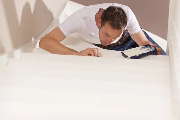 Young male painter painting indoor with paintbrush and white pai — Stock Photo, Image