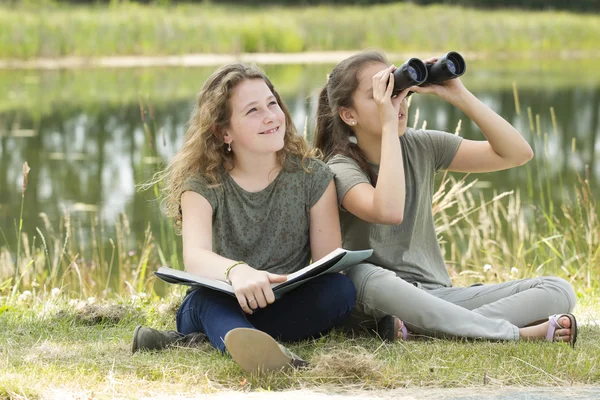 Hübsches junges Mädchen erkundet die Umgebung mit einem Fernglas Stockbild