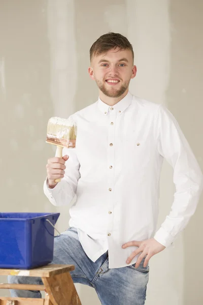 Glad ung man gör ett udda jobb i sitt nya hus — Stockfoto