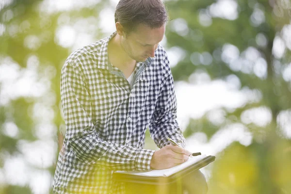 Environmentalist Writing On Notepad In Park — Stock Photo, Image