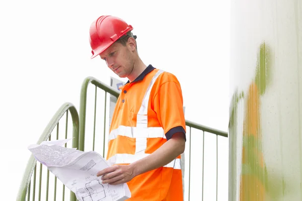 Arquitecto analizando el plan en pasos en el parque de tanques de almacenamiento —  Fotos de Stock