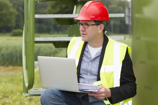 Arquiteto segurando plantas ao usar laptop — Fotografia de Stock